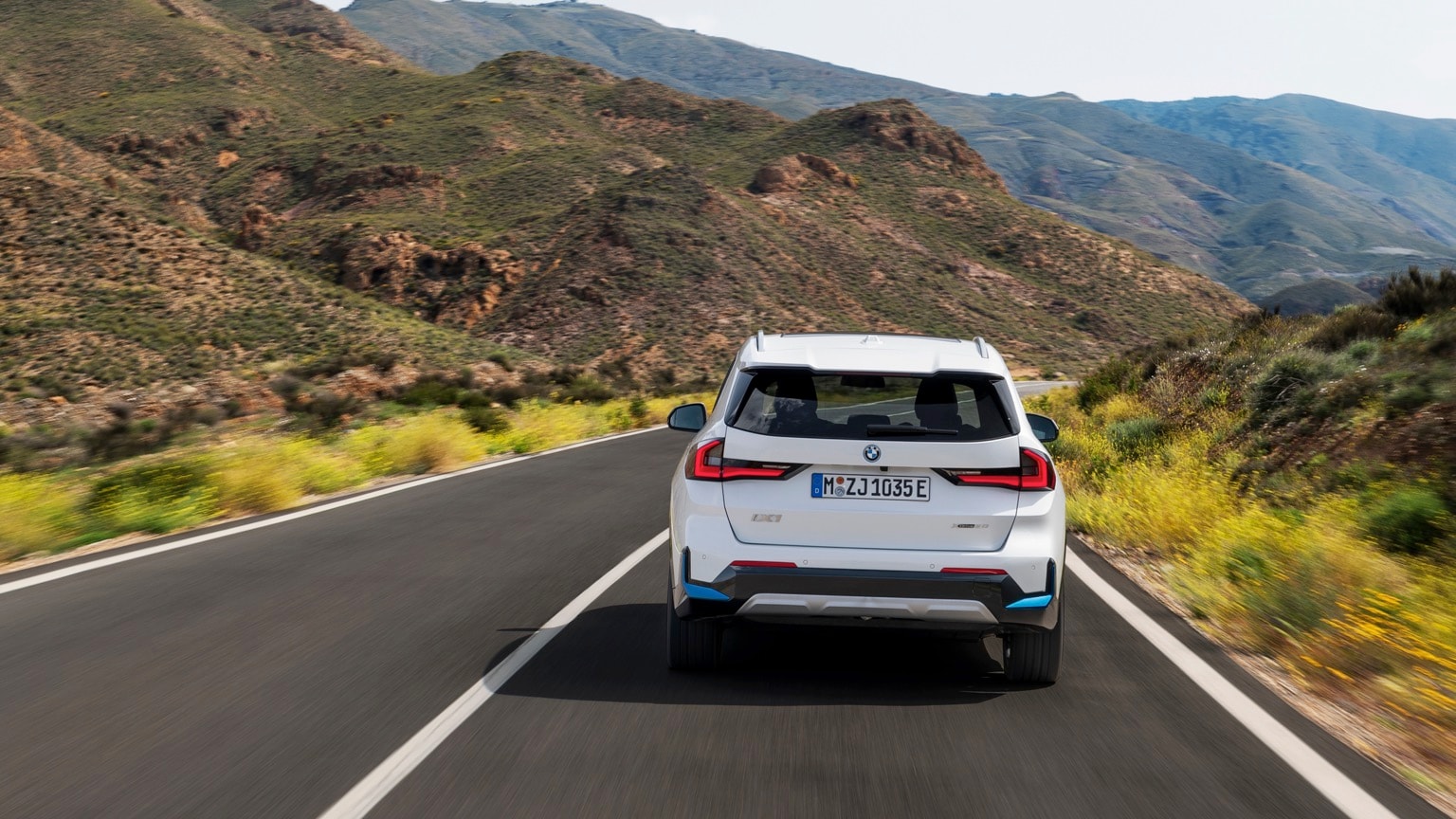 une voiture roulant sur une route avec des montagnes en arrière-plan