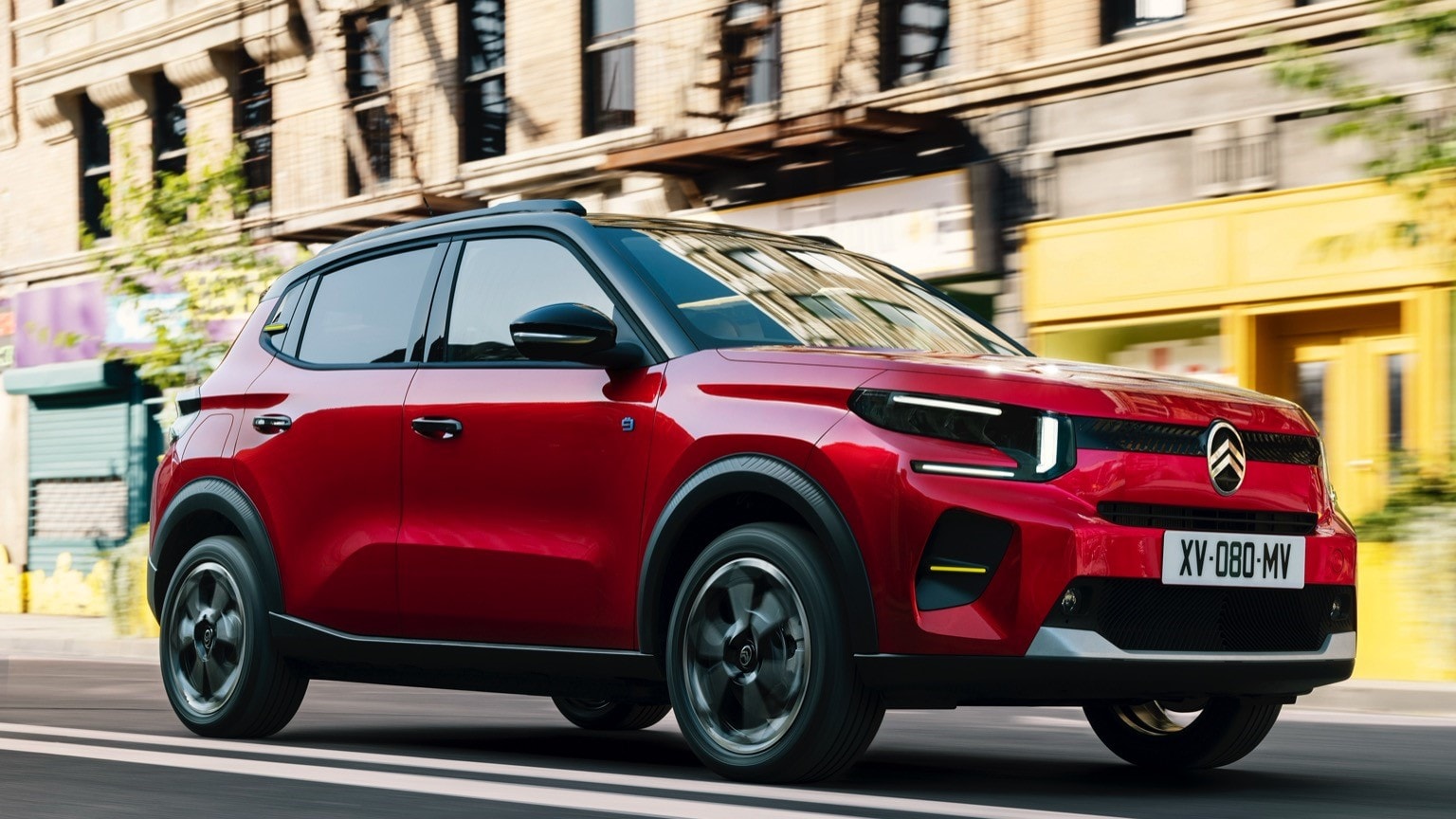 une voiture rouge roulant dans une rue