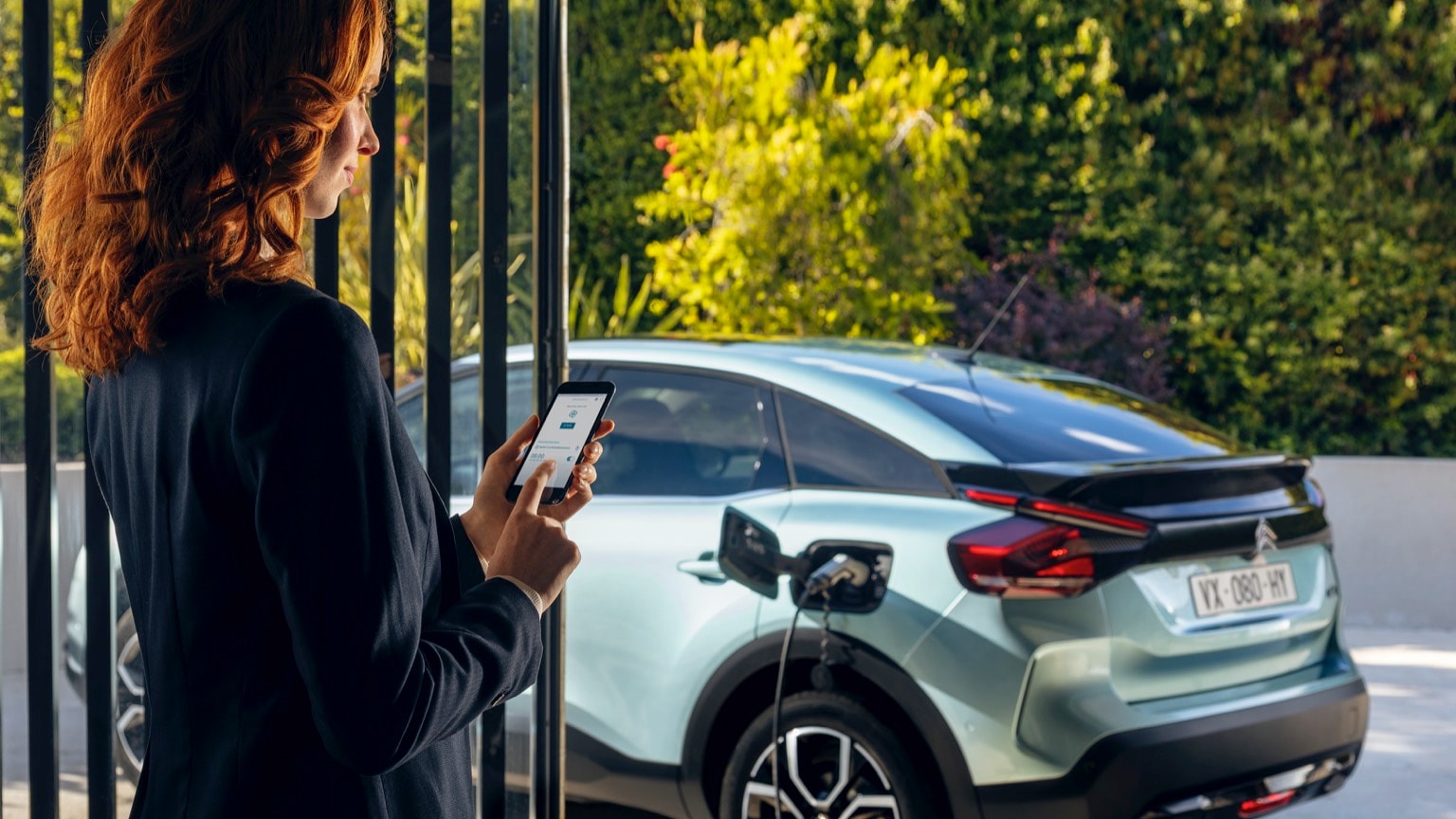 une femme tenant un téléphone à côté d'une voiture