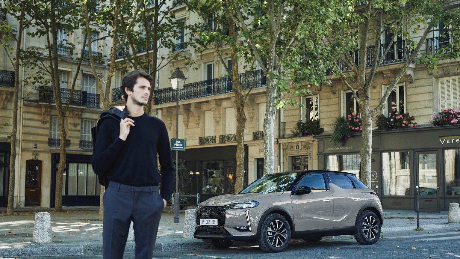 a man standing on a street with a car parked on the side