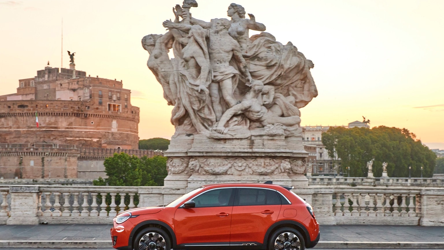 une voiture rouge garée sur un pont avec une statue de personnes
