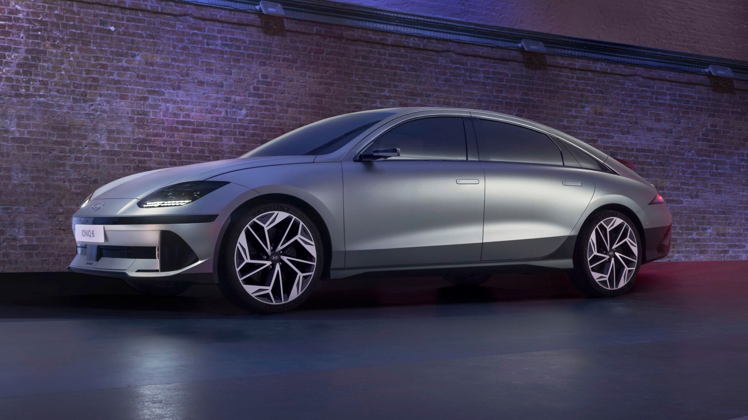 a silver car parked in front of a brick wall