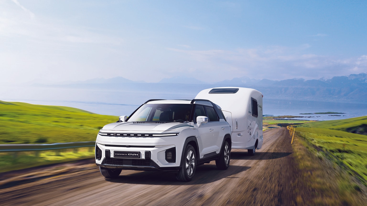 a white car with a trailer on a road
