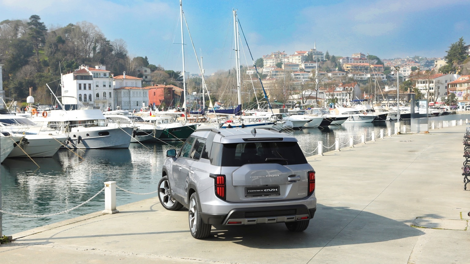a car parked on a dock near boats