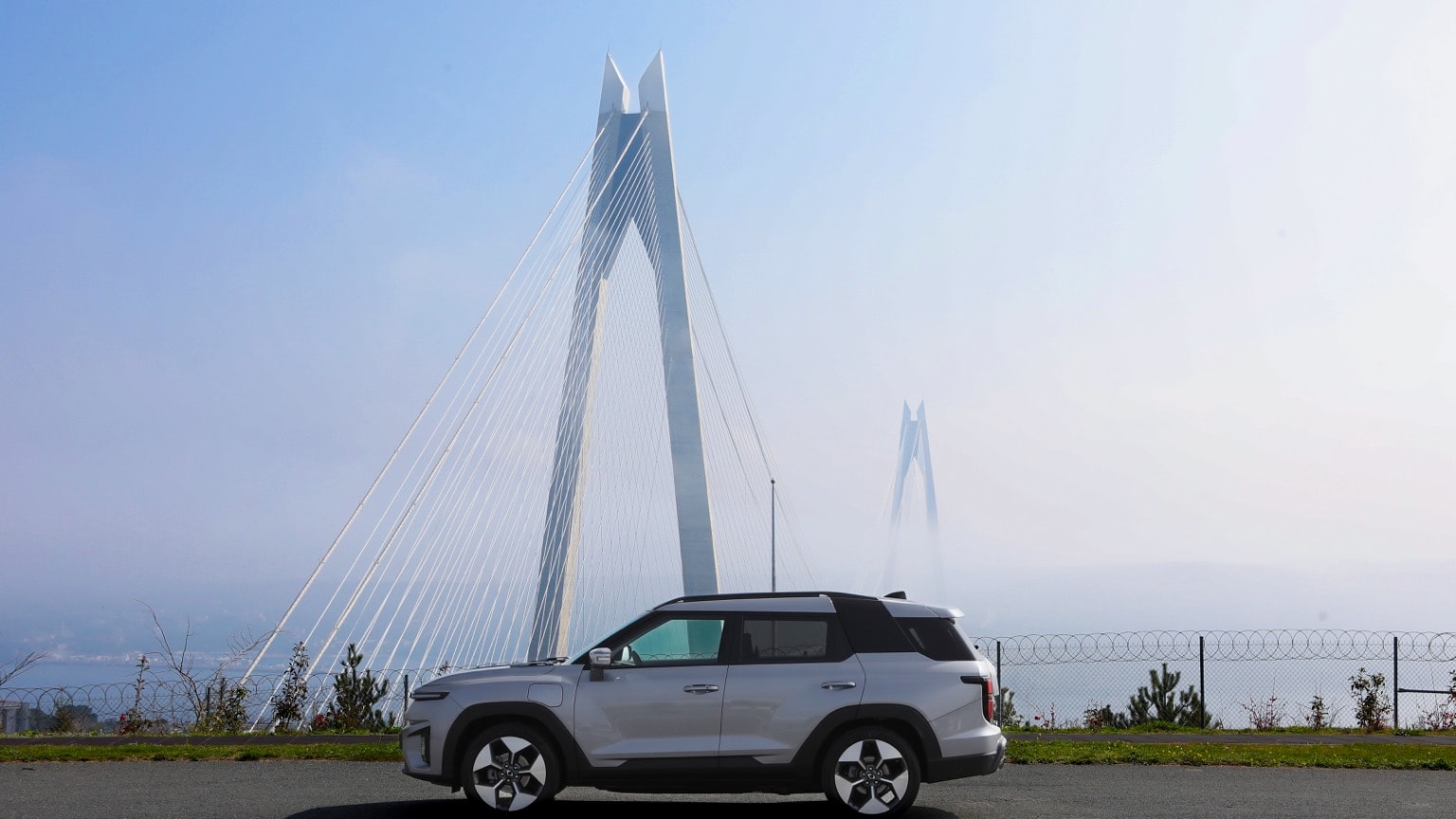 a car parked on a road with a large bridge in the background