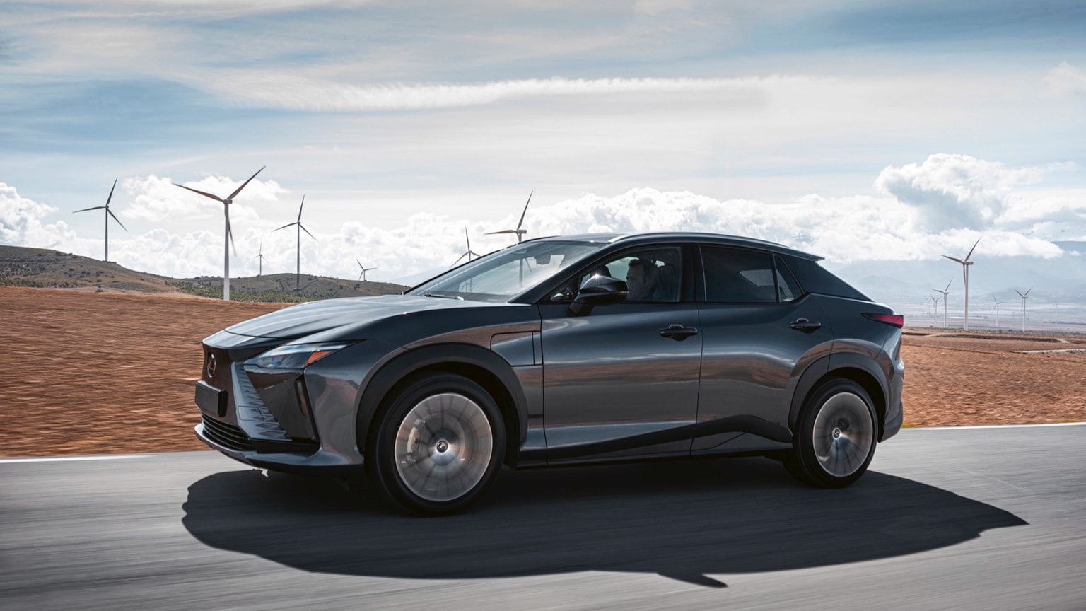 une voiture roulant sur une route avec des éoliennes en arrière-plan