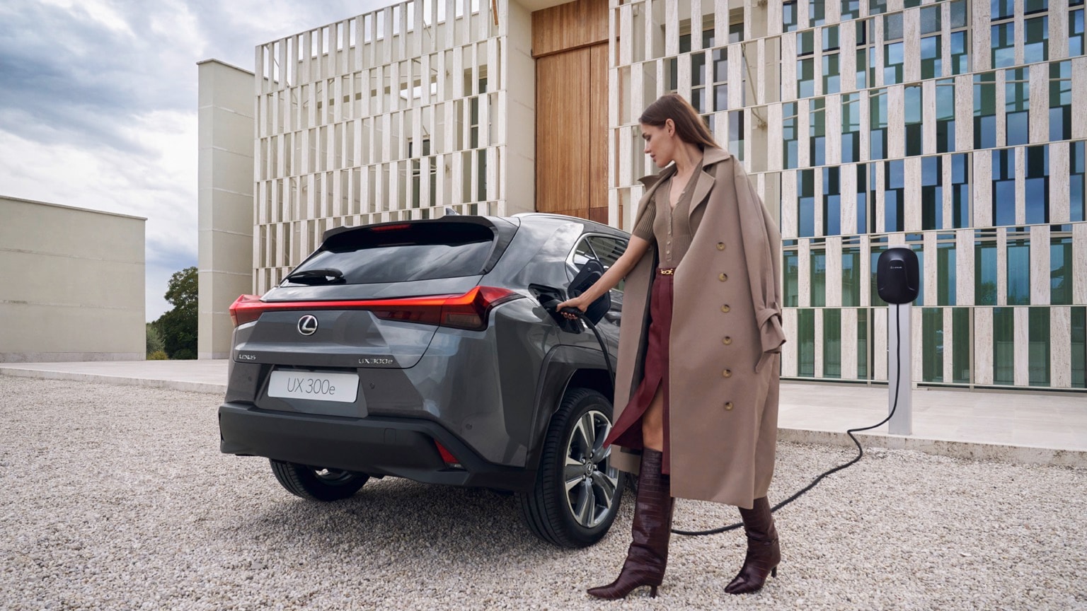 une femme vêtue d'un long manteau et de bottes hautes charge une voiture
