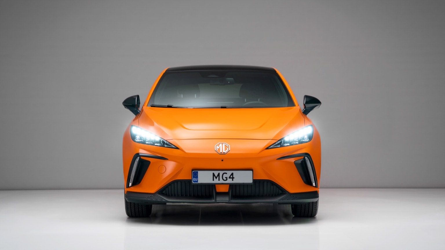 an orange sports car with its headlights turned on