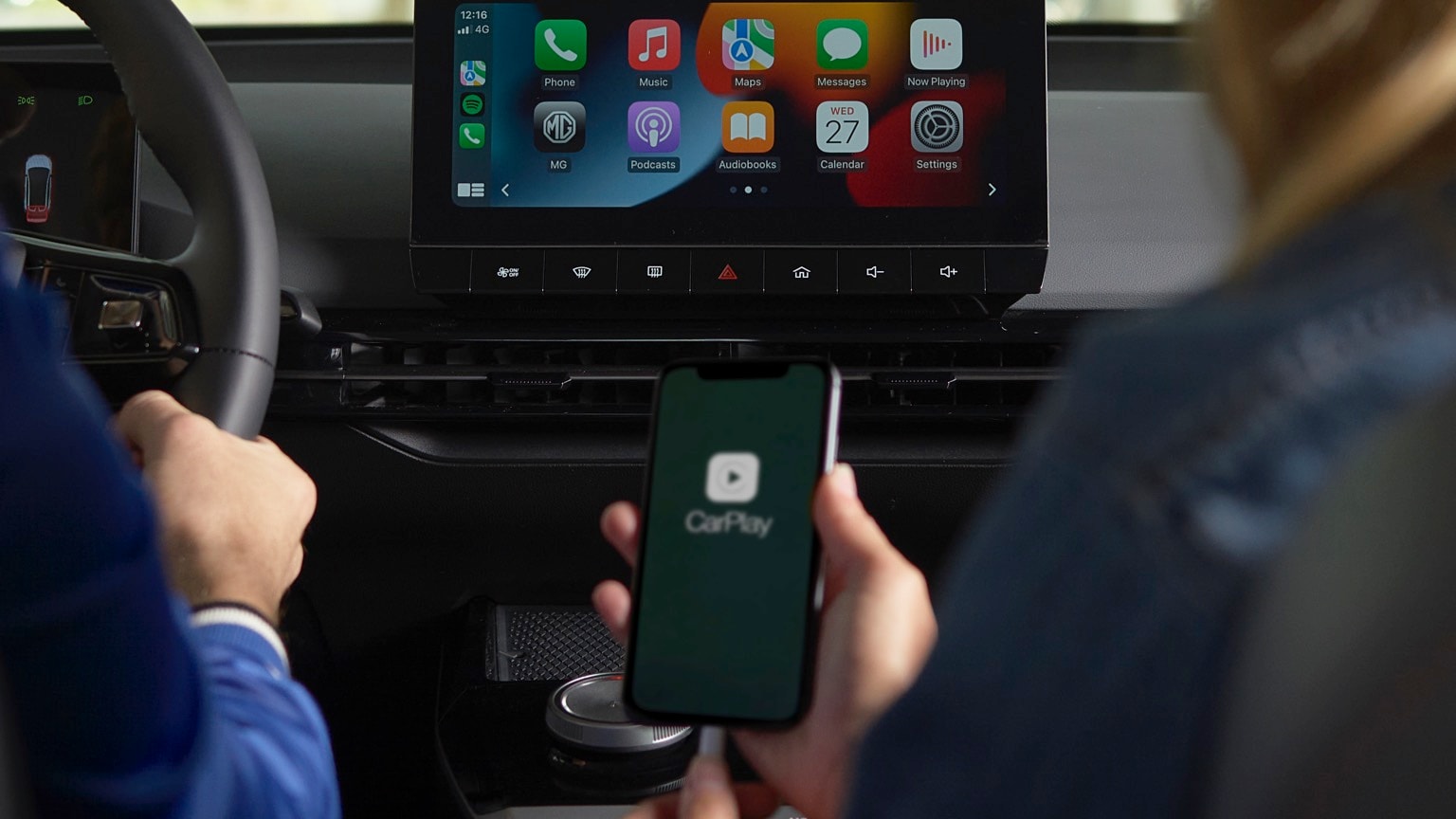 a person holding a phone in front of a car