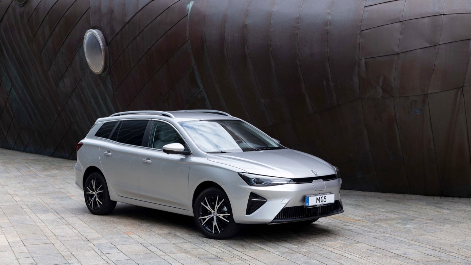 a silver car parked in front of a large metal ship