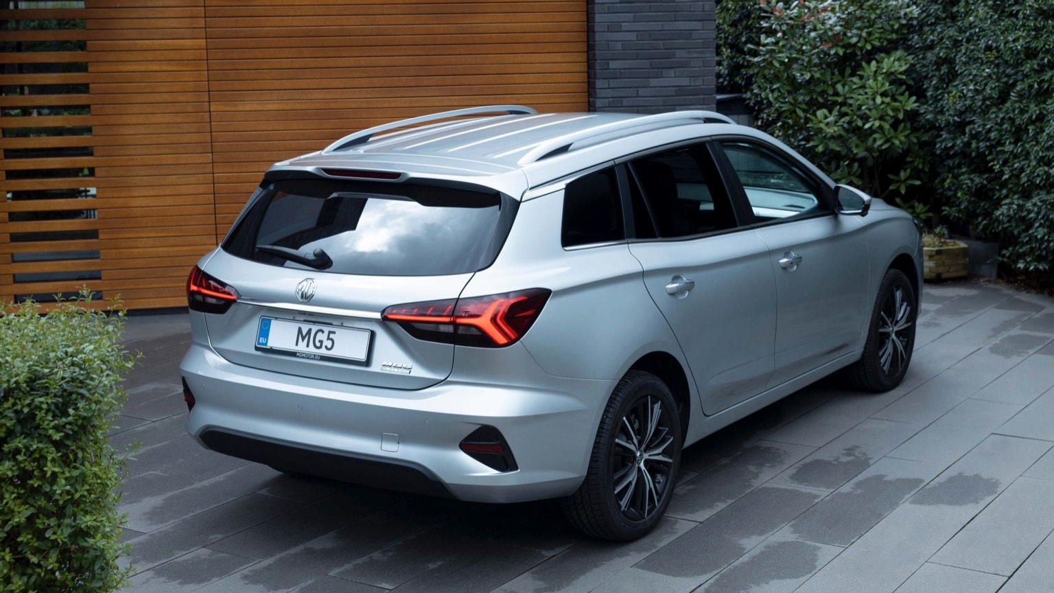 a silver car parked in front of a wood wall