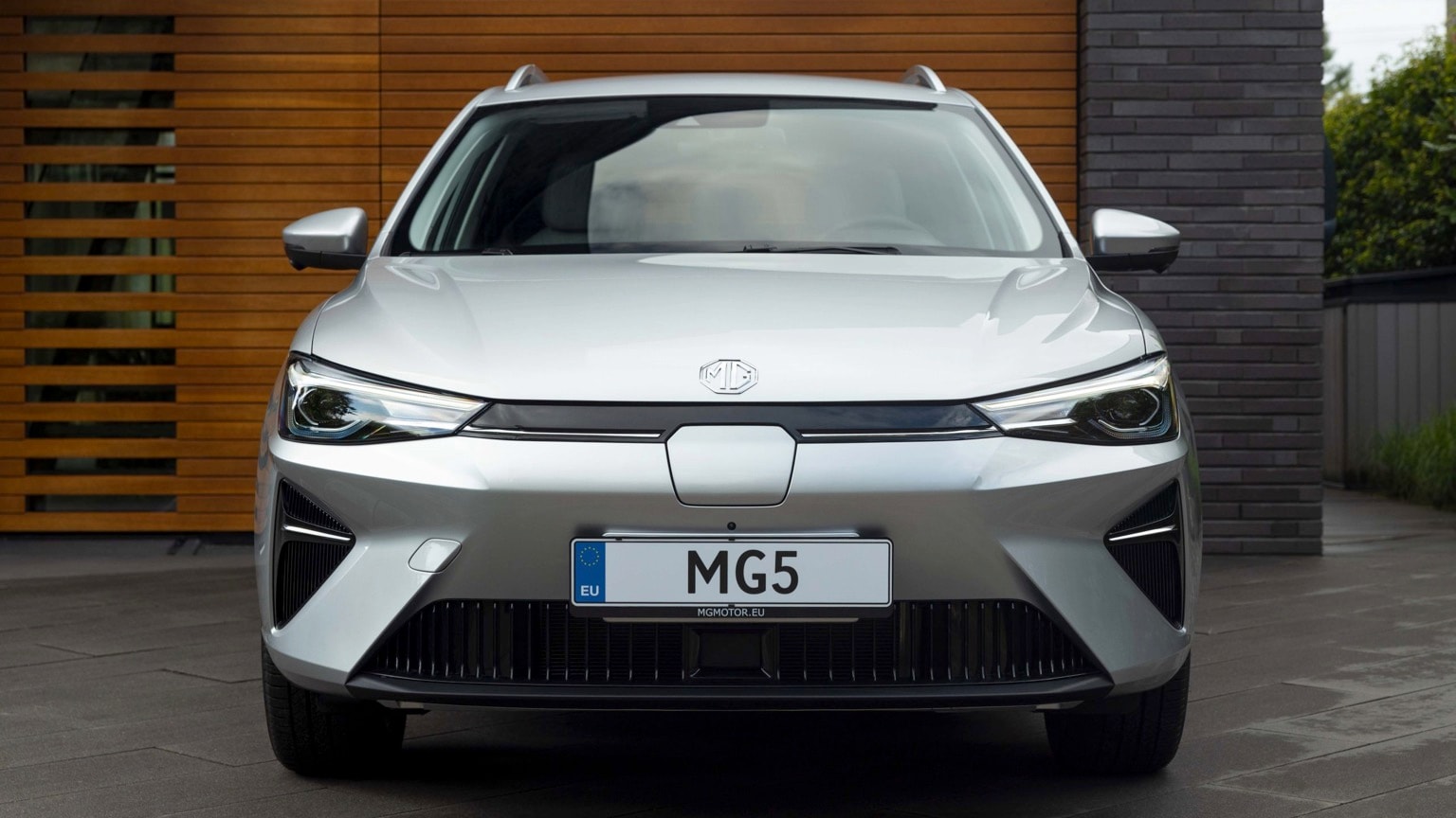 a silver car parked in front of a wood wall