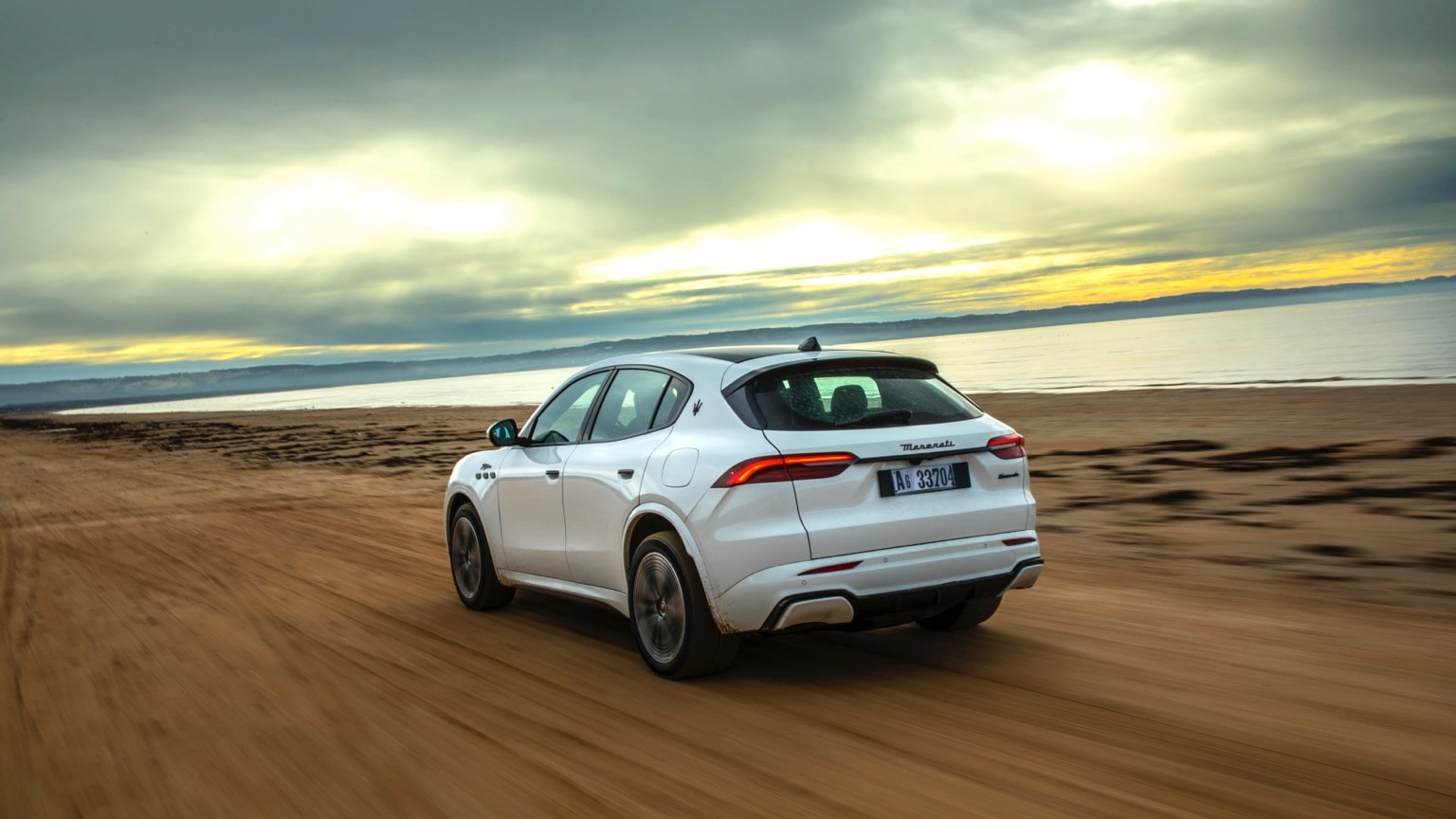une voiture blanche roulant sur une plage de sable