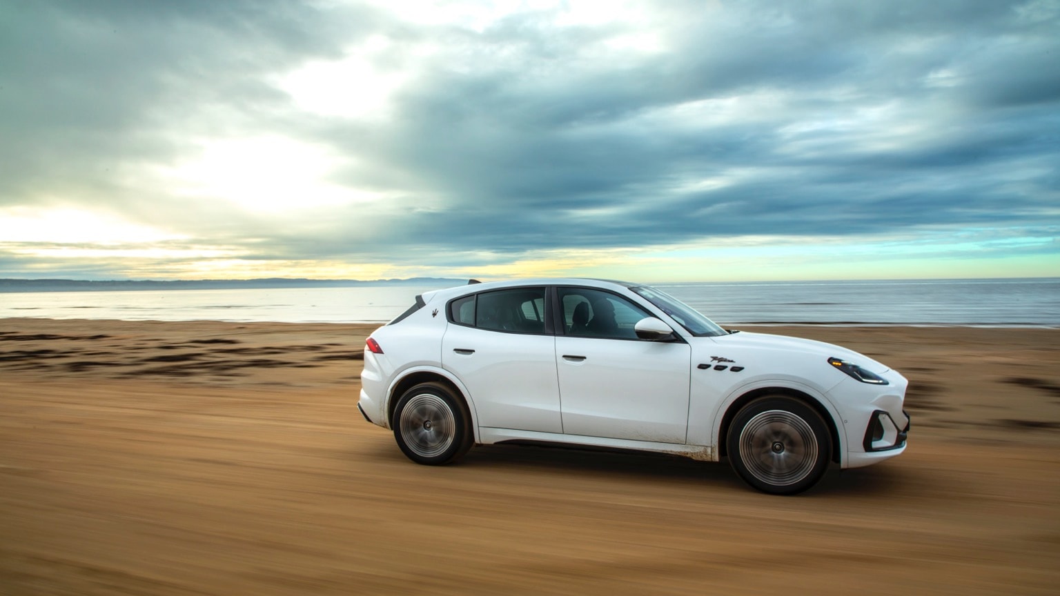 une voiture blanche roulant sur une plage de sable