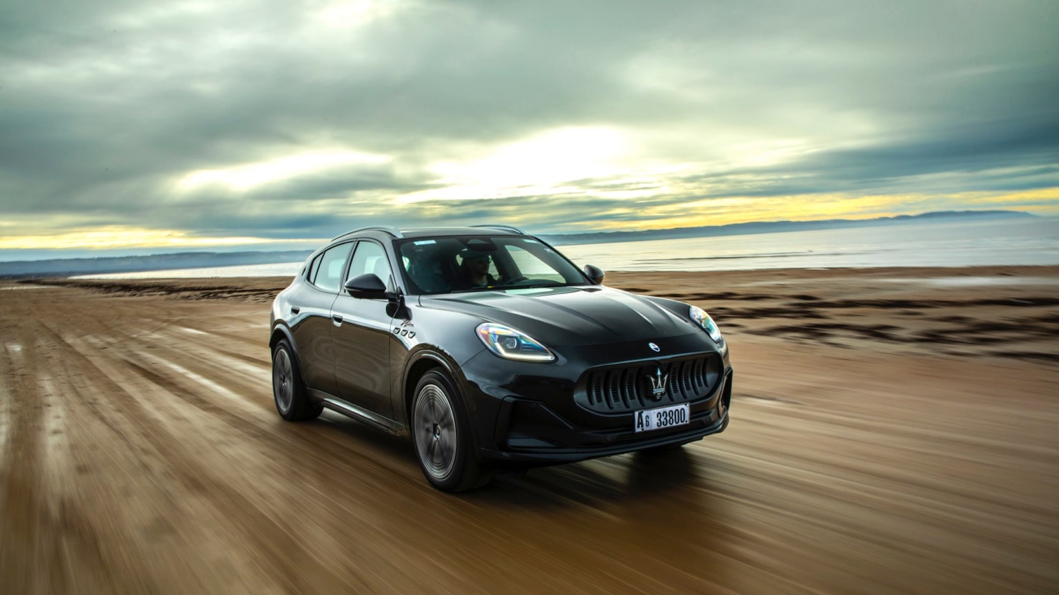 une voiture noire roulant sur une plage de sable
