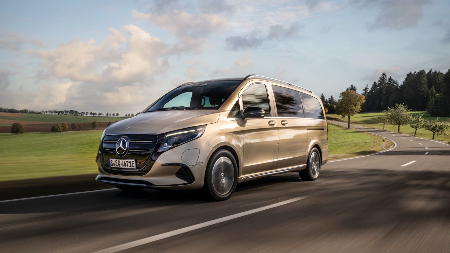 a gold van driving on a road