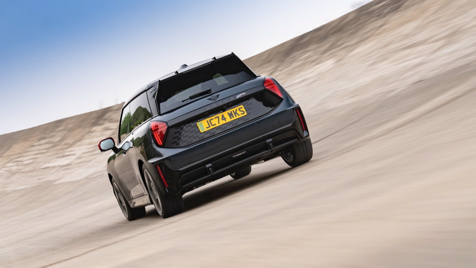 a black car driving on a sandy road