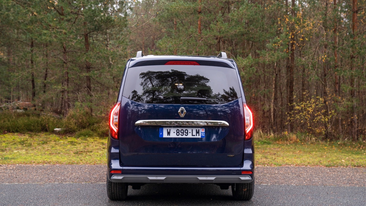 une camionnette bleue garée sur une route avec des arbres en arrière-plan