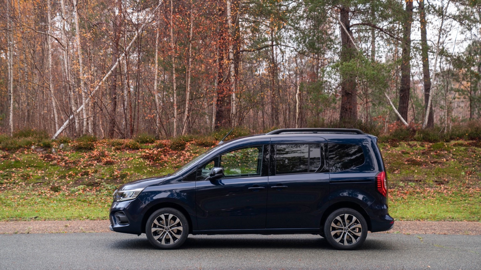 une camionnette bleue garée sur une route avec des arbres en arrière-plan
