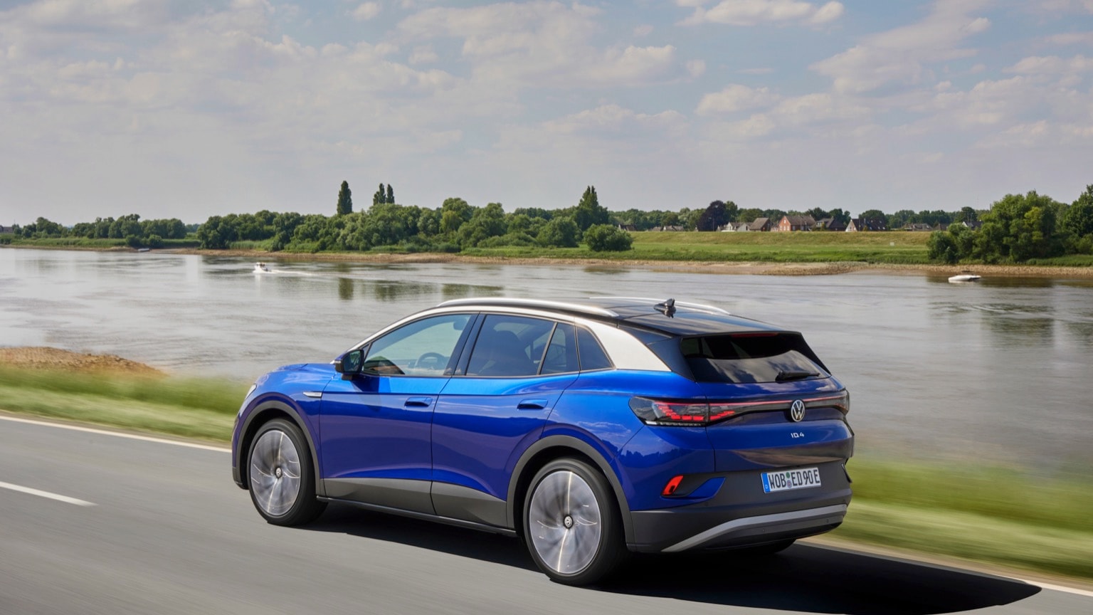 une voiture bleue roulant sur une route près d'un plan d'eau