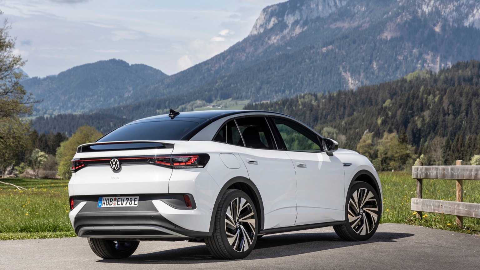 a white car on a road with mountains in the background