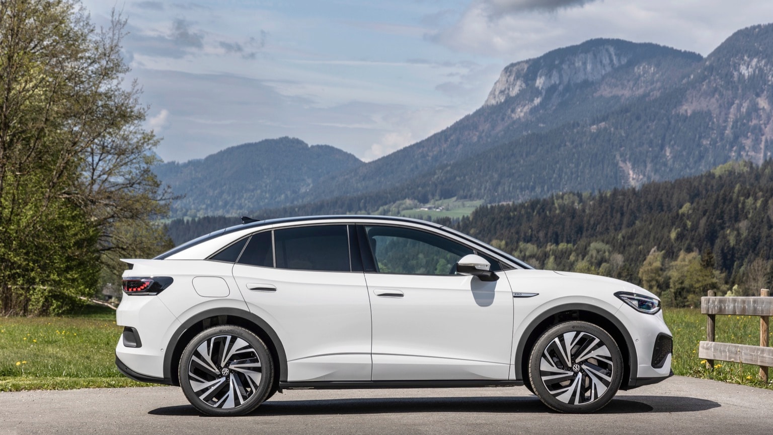 a white car parked on a road with mountains in the background