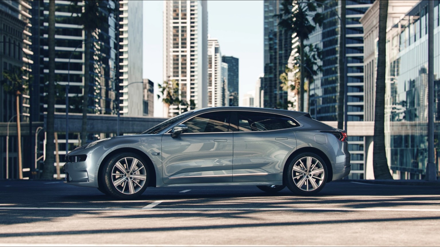 a silver car parked on a street with tall buildings in the background